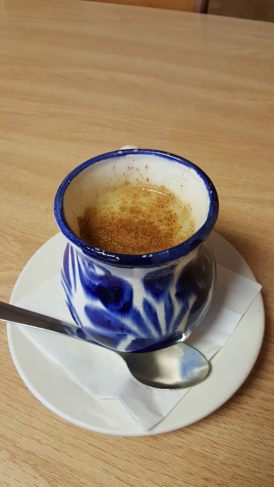 A cup of warm champurrado dusted with cinnamon in a traditional Talavera mug
